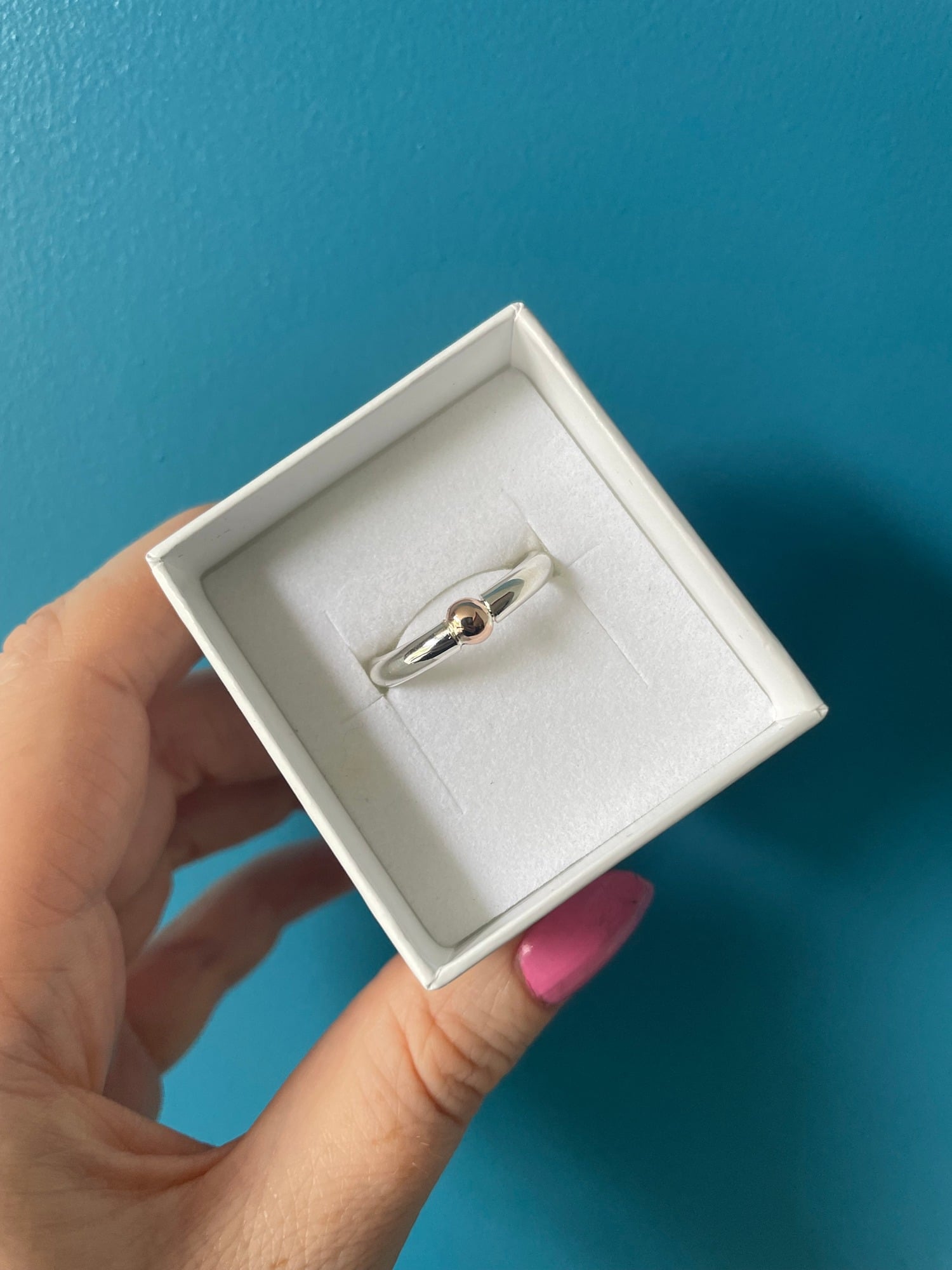 Minimalist silver Solis ring with gold ball tension-set style in box.