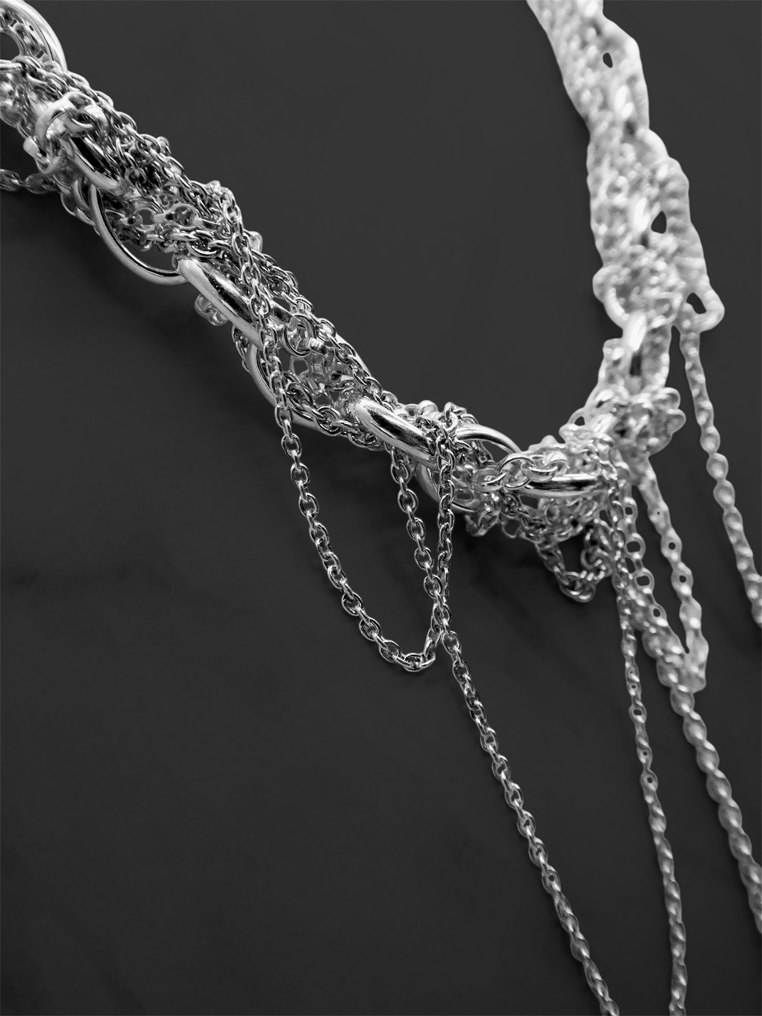 A collection of unusual necklaces for women, including chunky multi-chain and Art Deco silver pendants.