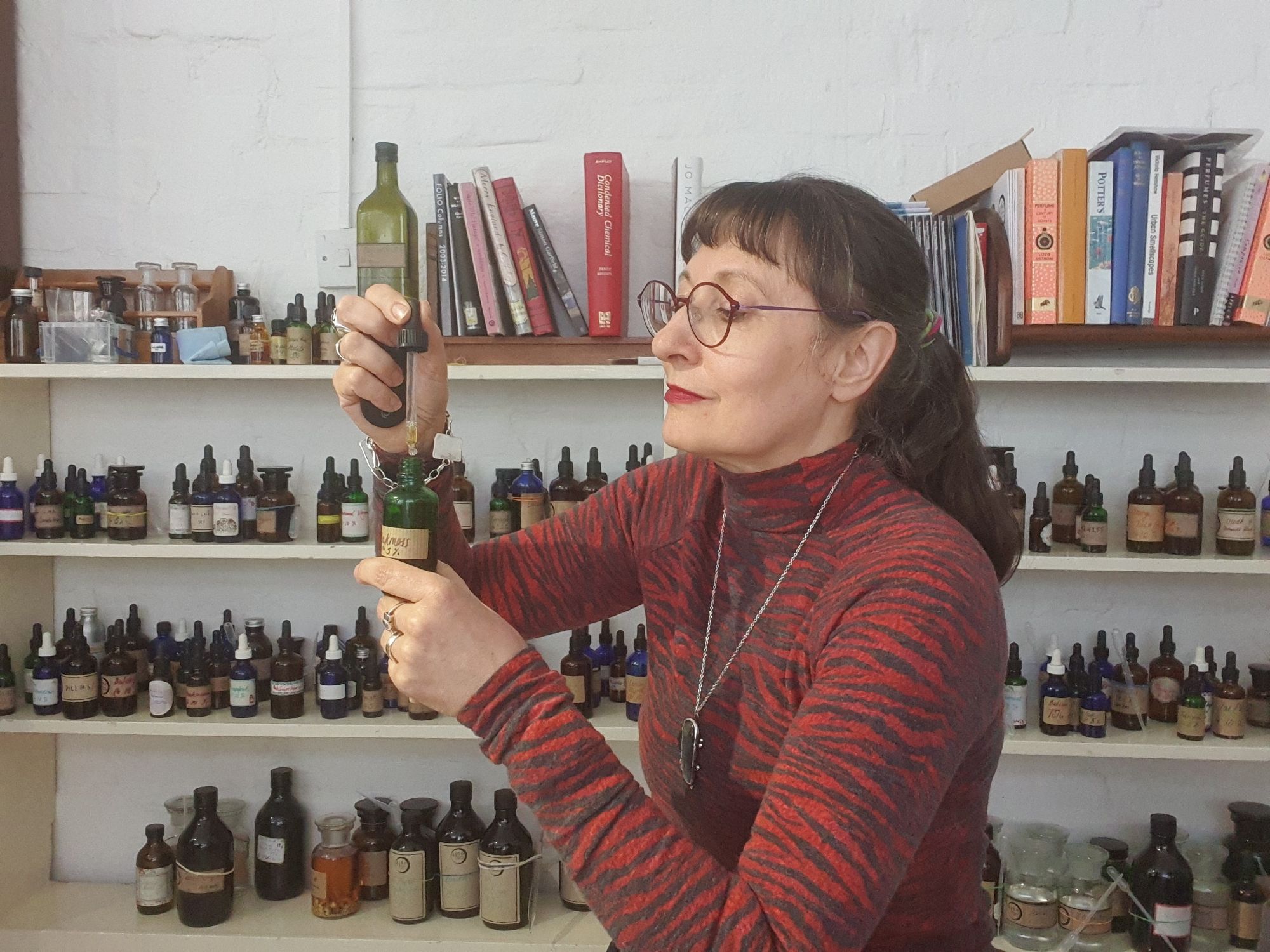 Perfumer Sarah McCartney in front of a shelf full of perfume materials