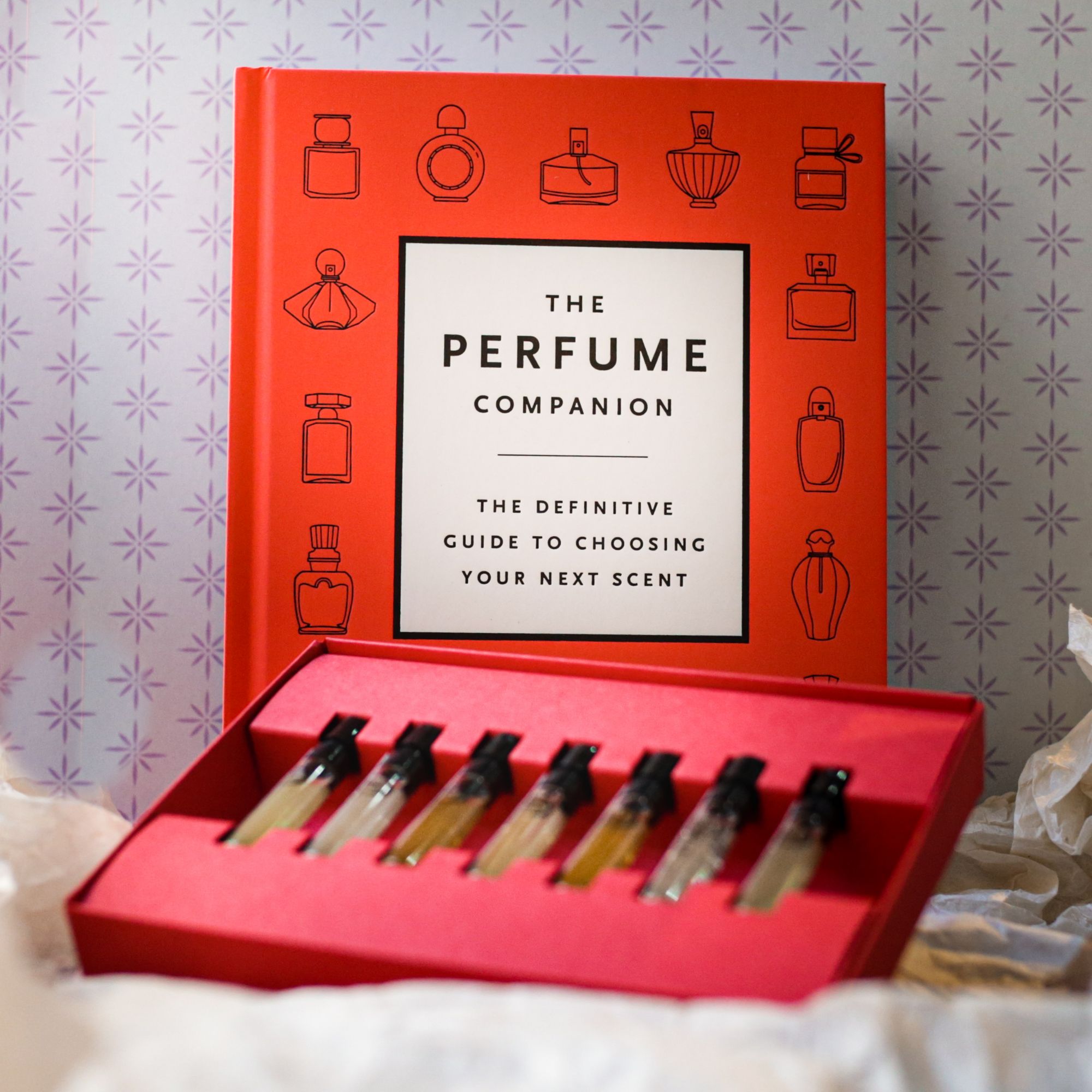 A bottle of 4160 Tuesdays perfume against a blue swirling backdrop