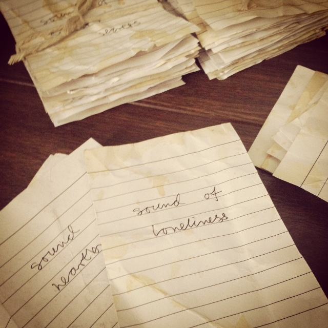 Several paper cards with different prompts to listen written on them, such as 'Sound of loneliness' 