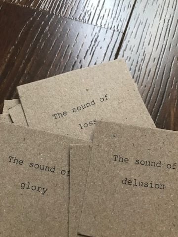 A number of notecards with typed text. the only visible one reads 'the sound of loss' 