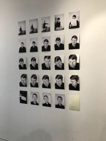 A number of black and white closeup pictures hanging on the wall. They all show closeups of the artist, a white woman with short hair. 