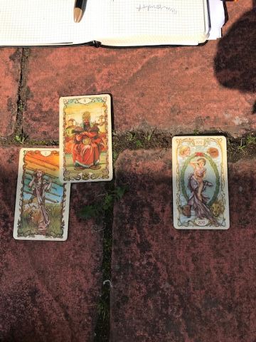 Three tarot cards on stone garden stones 