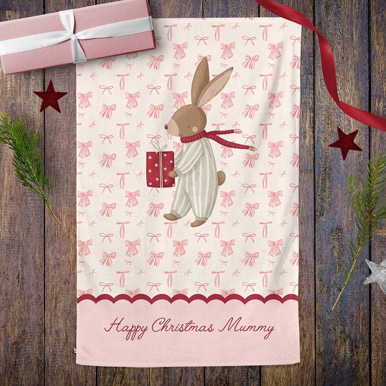 Personalised cotton Christmas tea towel with hand-drawn festive bunny illustration on a background of pink bows
