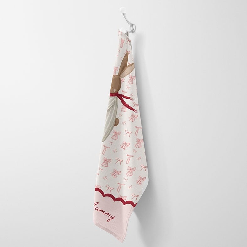 Personalised cotton Christmas tea towel with hand-drawn festive bunny illustration on a background of pink bows