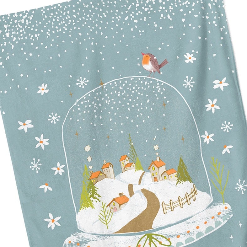 Personalised cotton Christmas tea towel in pale blue with snowy hand-drawn snowglobe village illustration