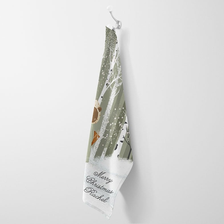 Personalised cotton Christmas tea towel in sage green and white with snowy hand-drawn festive illustration