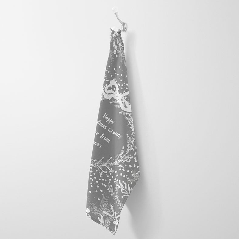 Personalised cotton Christmas tea towel in pale grey and white with white winter wreath, leaves, and berries