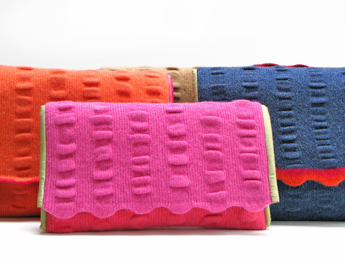 Selection of brightly coloured and felted SLOANmade bags standing on white background