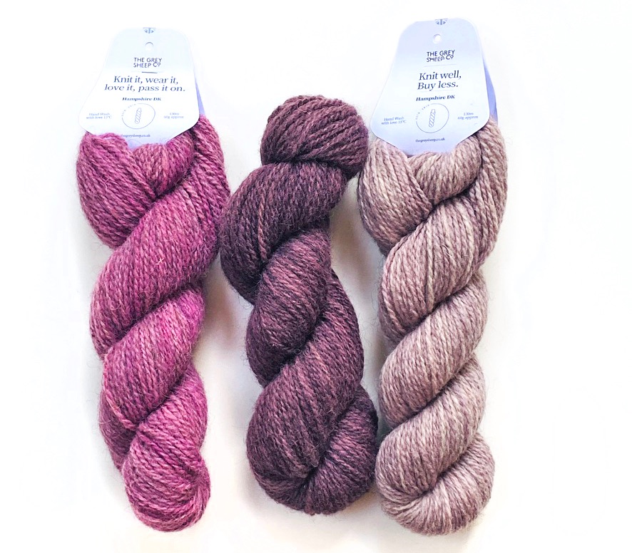 three skeins of Hampshire DK yarn in The Berries colourway lying on white background