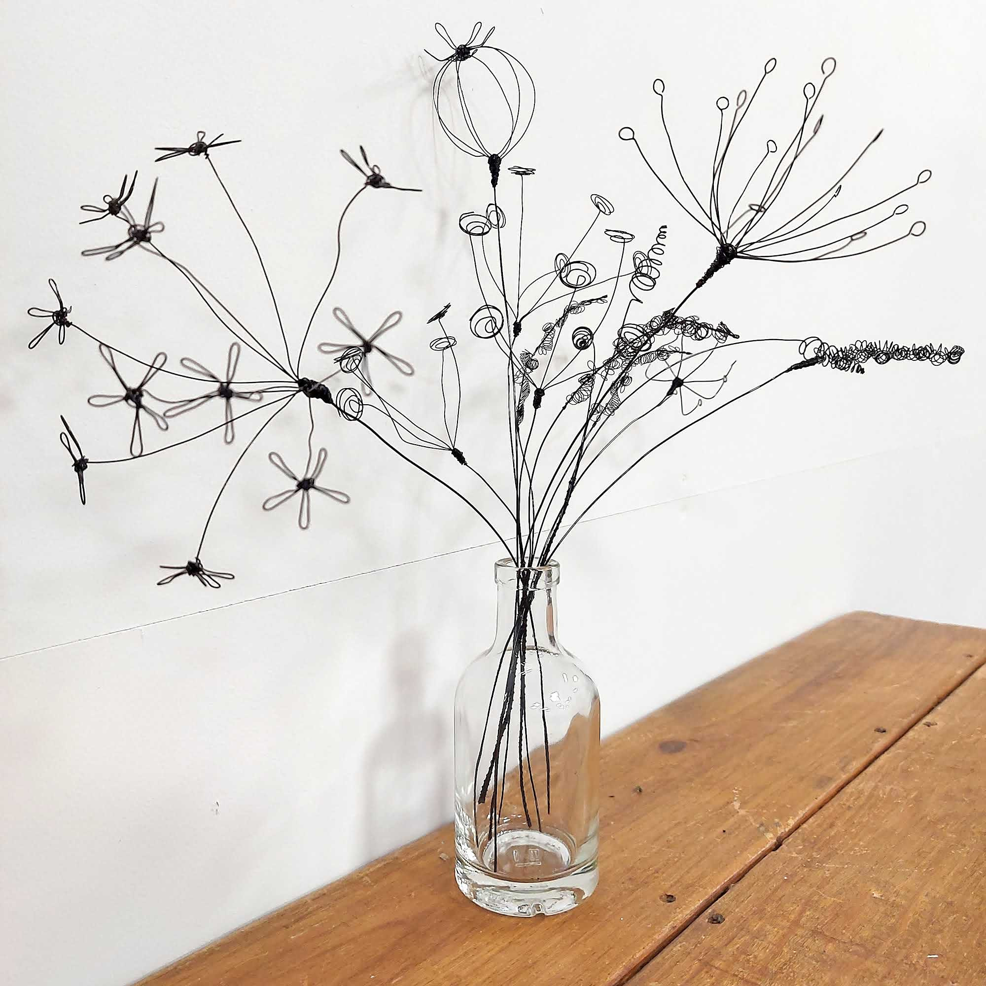 Black wire seed heads in a glass bottle made on a workshop with Judith Brown