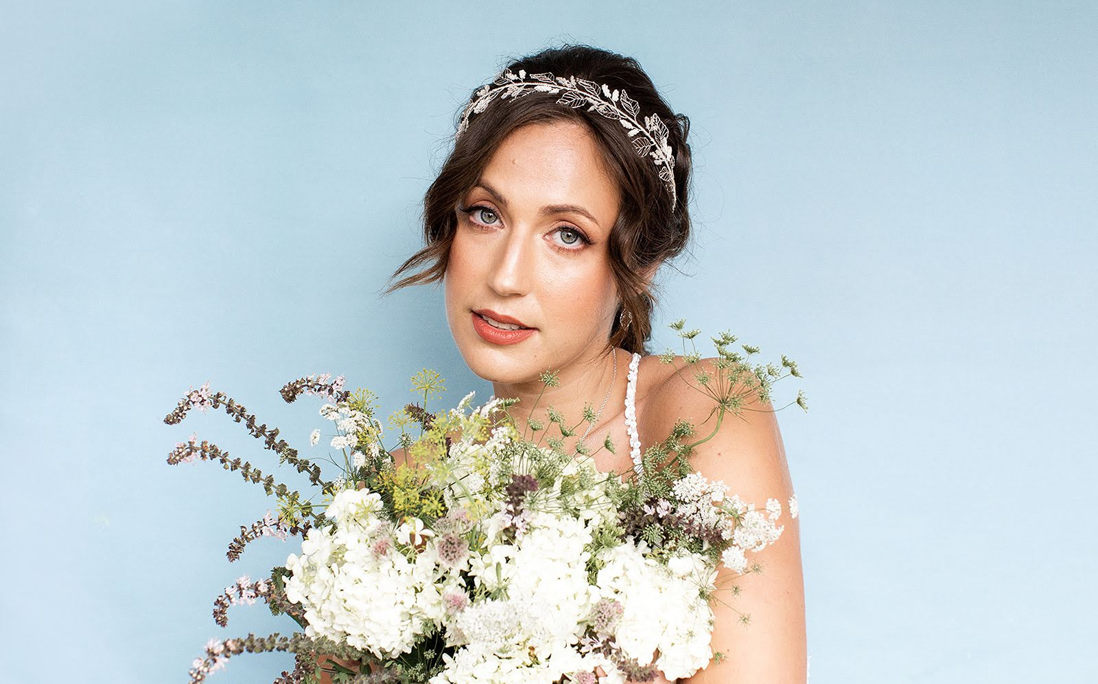 A bride carrying wiidflowers and wearing a silver leaf hair vine