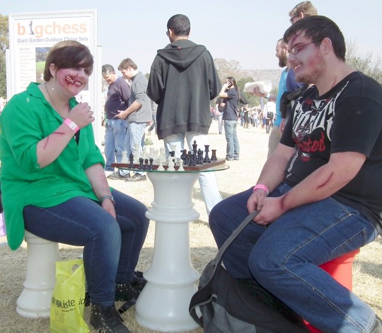 A smiling couple playing "small" chess at the queen table and sitting on castles.