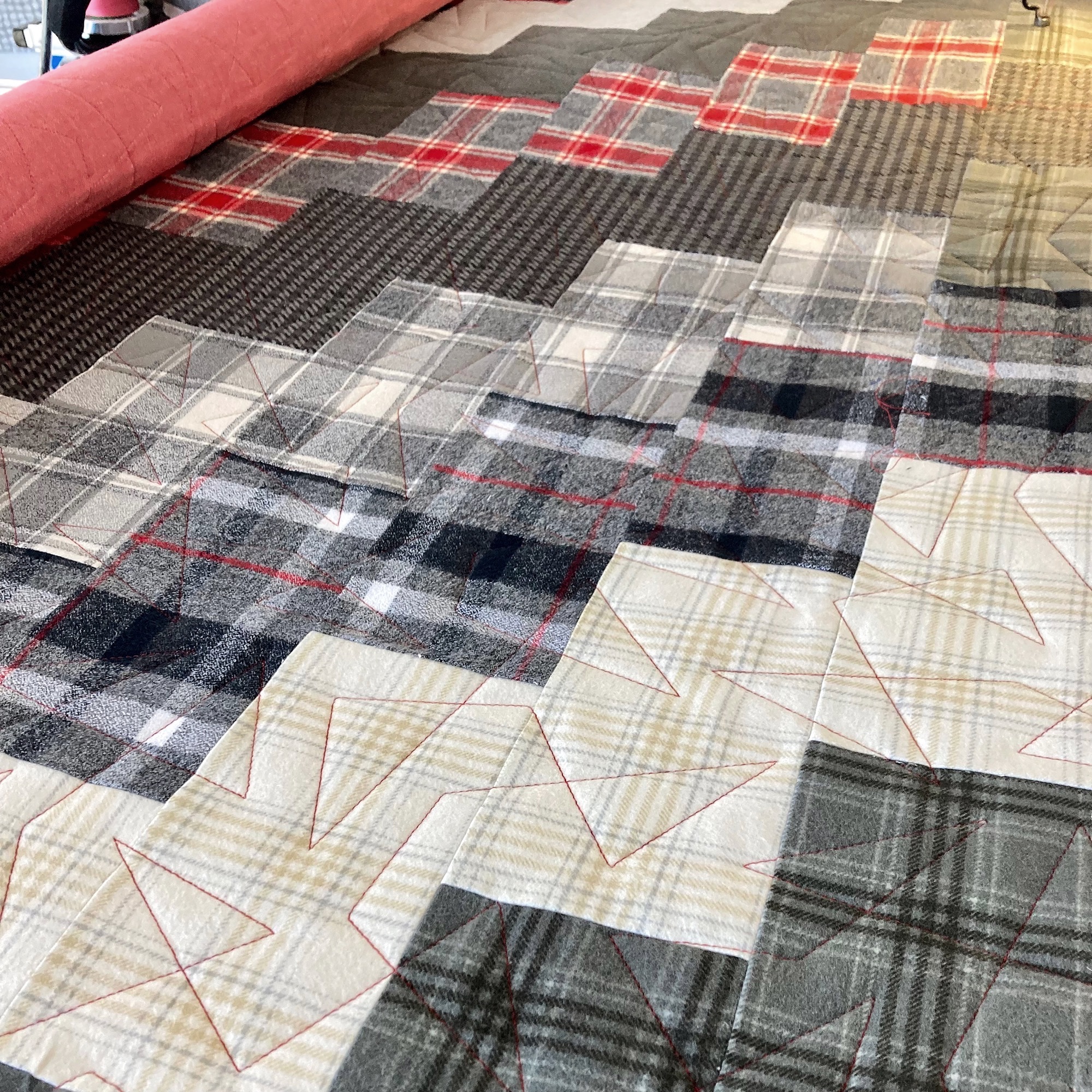 Flannel quilt on a longarm frame stitched with a geometric pantograph