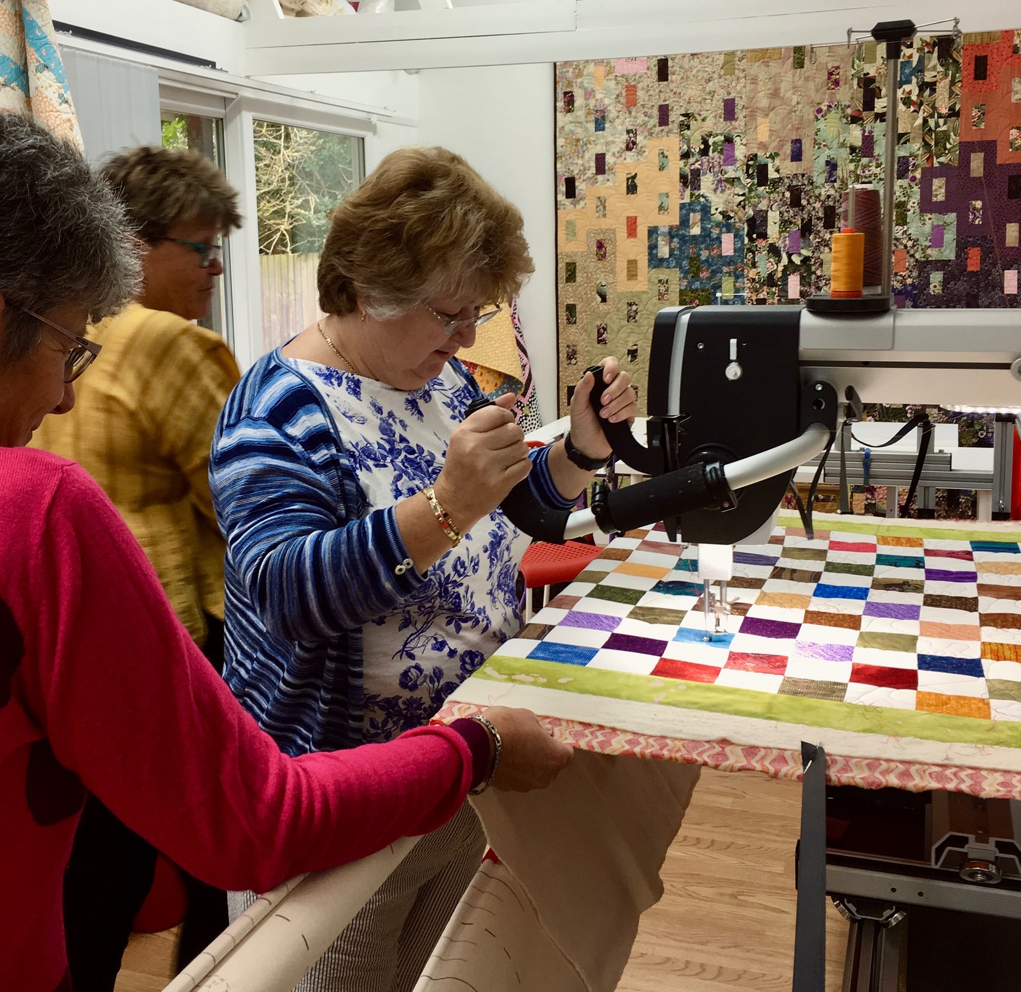 Image of a group of ladies  using a longarm quilting machine