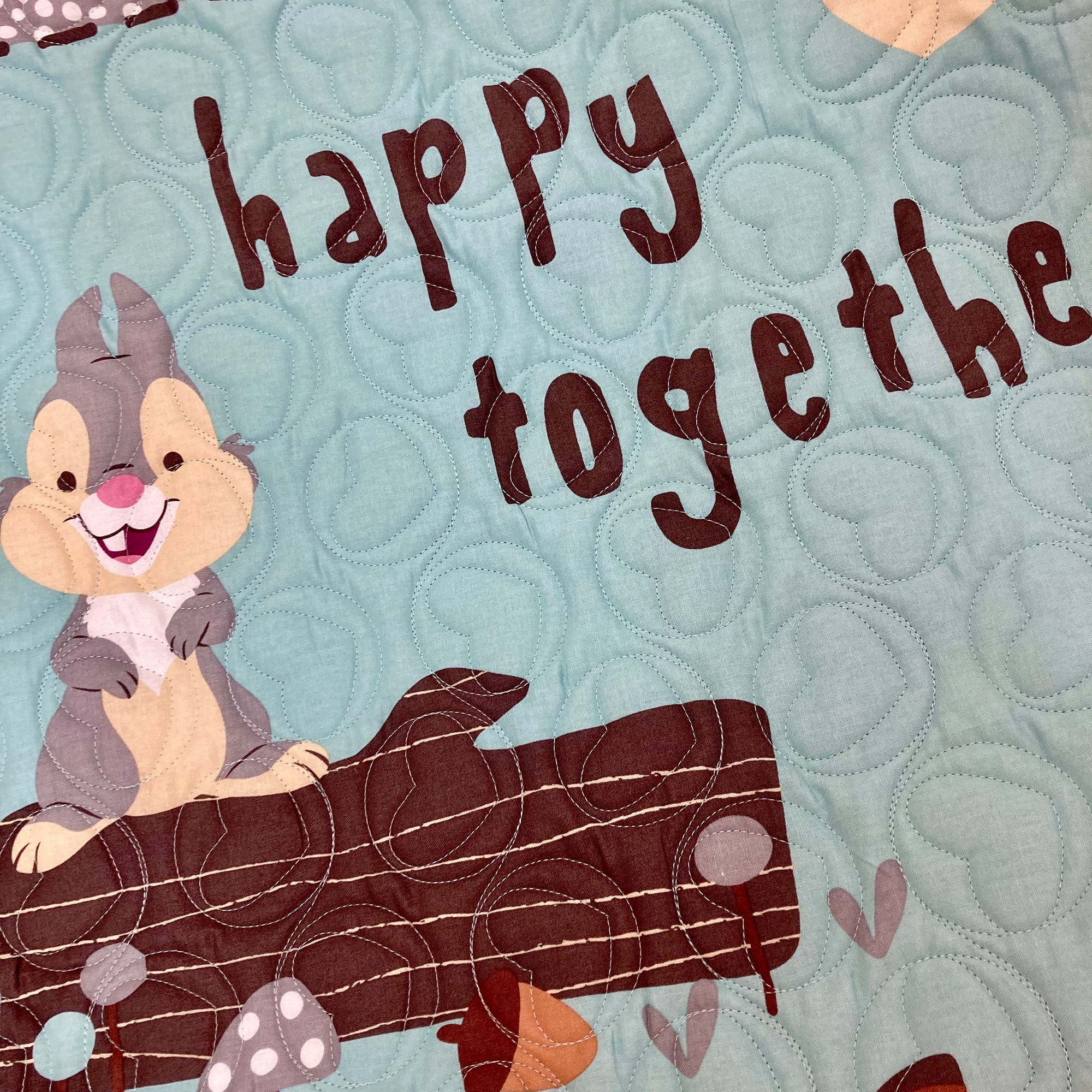 Photo of a quilt with a rabbit on a tree saying happy together