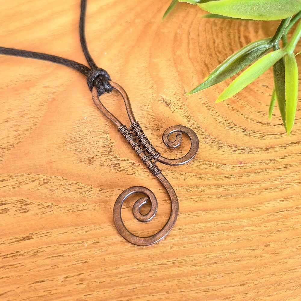 Copper scroll pendant mounted on an adjustable black cord
