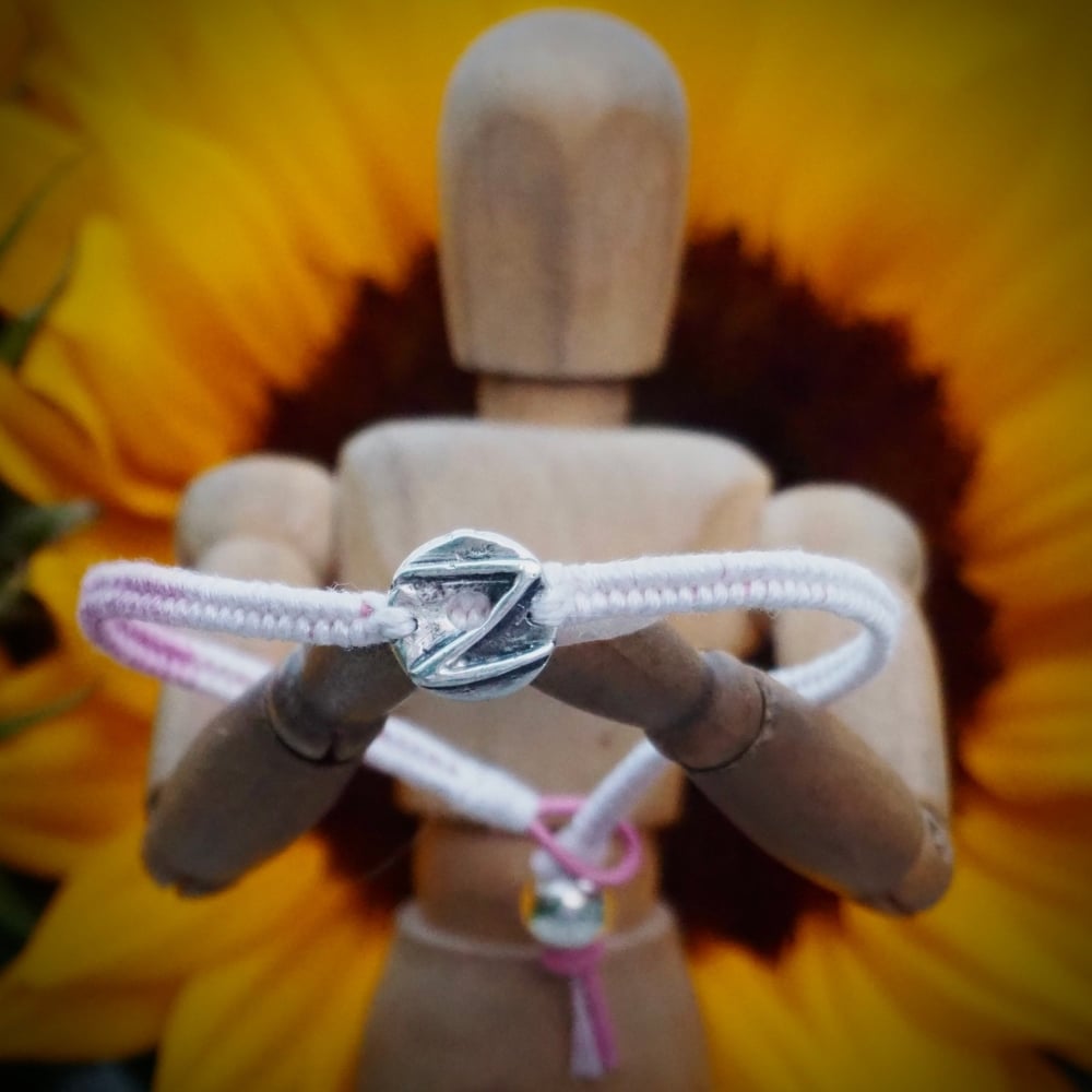 Fine silver glazed donut charm on a soft pink friendship bracelet