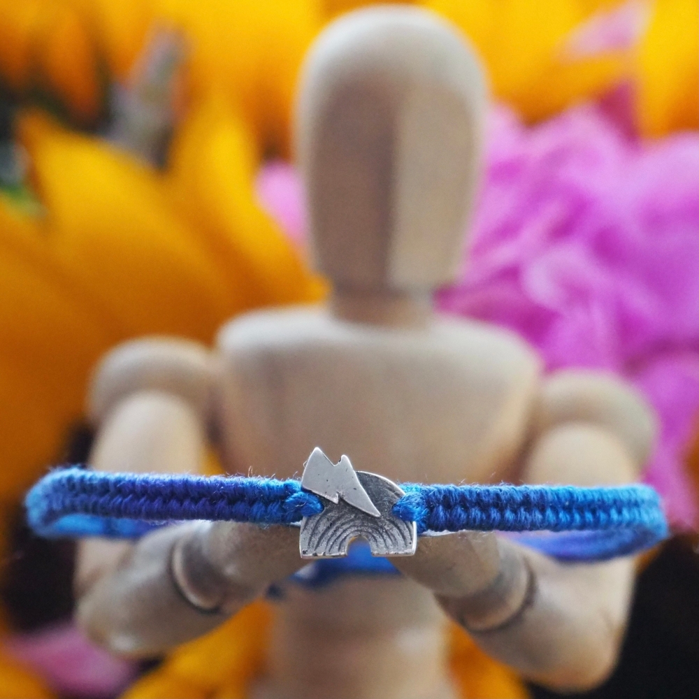Fine silver rainbow and lightning charm on a deep blue friendship bracelet