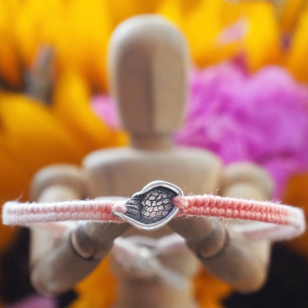 Fine silver angel wing charm on a peach friendship bracelet