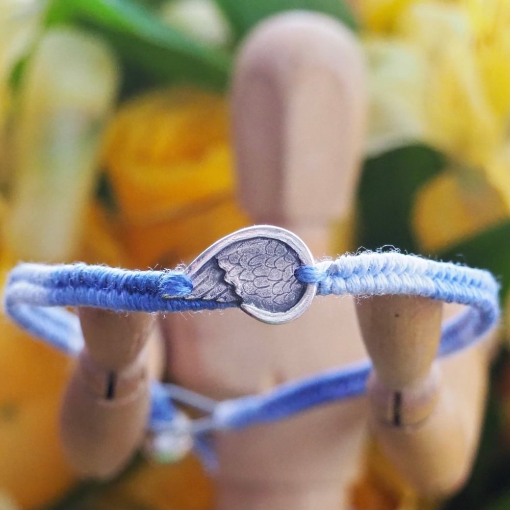 Fine silver angel wing charm on a blue friendship bracelet