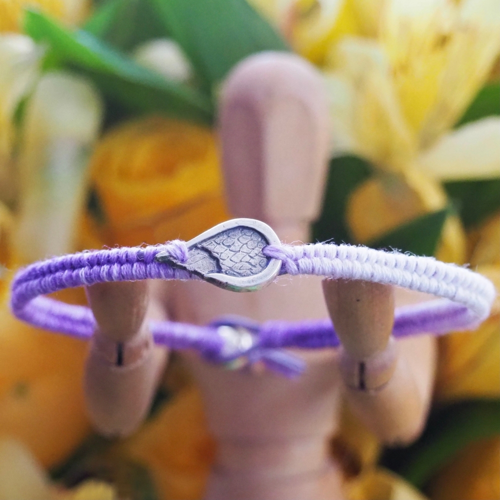 Fine silver angel wing charm on a purple friendship bracelet