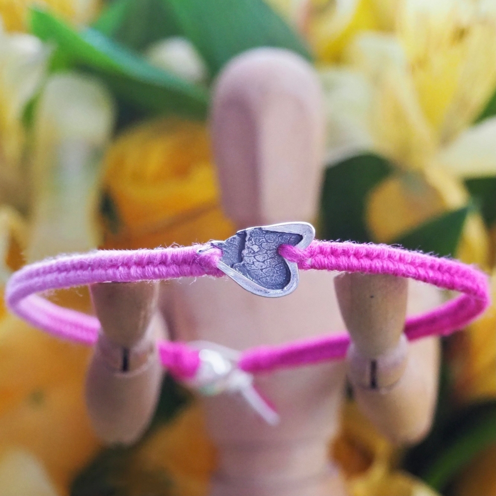 Fine silver angel wing charm on a pink friendship bracelet