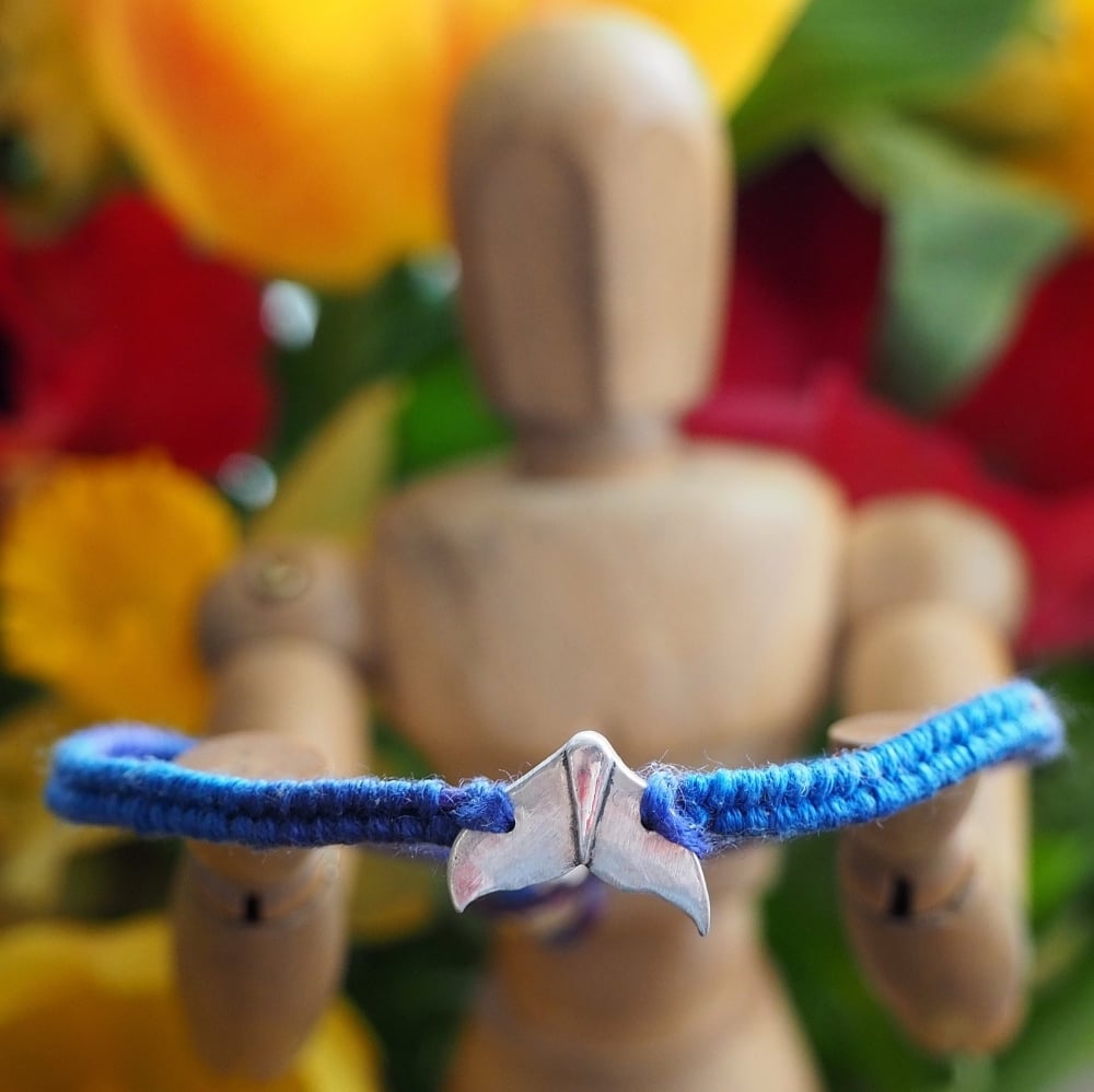 Fine silver whale tail charm on a blue friendship bracelet