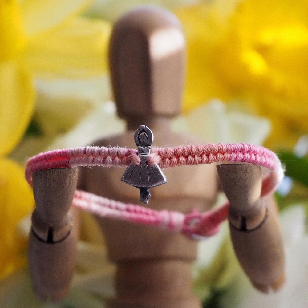 Fine small silver ballerina charm on a baby pink friendship bracelet