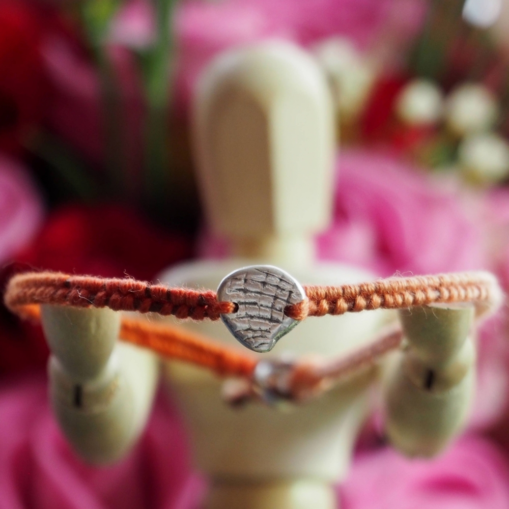 Fine silver clam shell charm on a orange/brown friendship bracelet