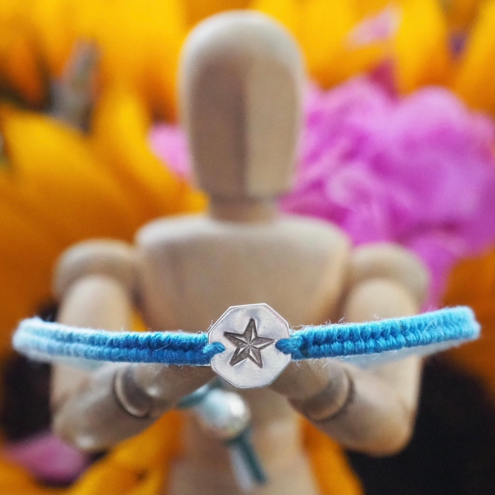 Fine silver hexagon charm with star stamp on a blue friendship bracelet