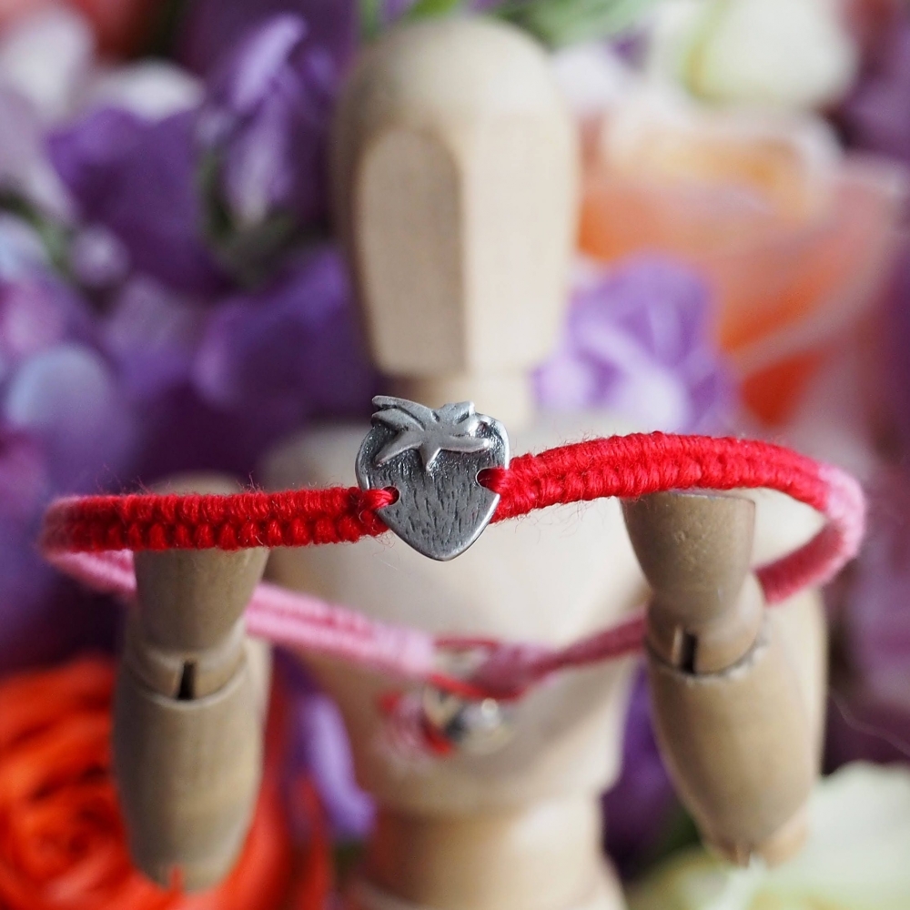 Fine silver strawberry charm on a red friendship bracelet