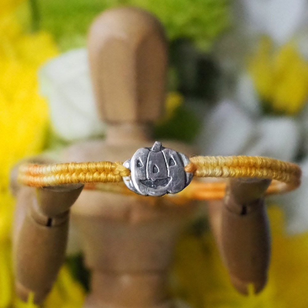 Fine silver pumpkin charm on an orange friendship bracelet