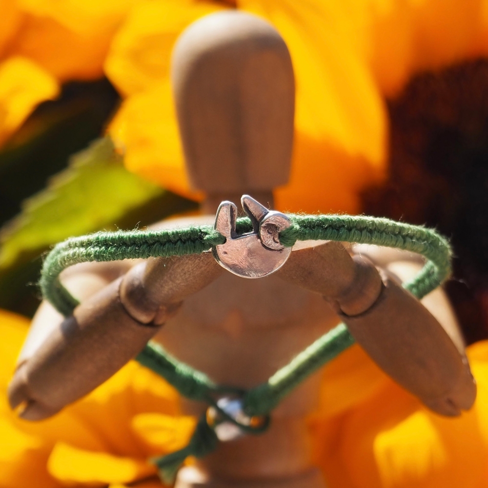 Fine silver sloth charm on a green friendship bracelet