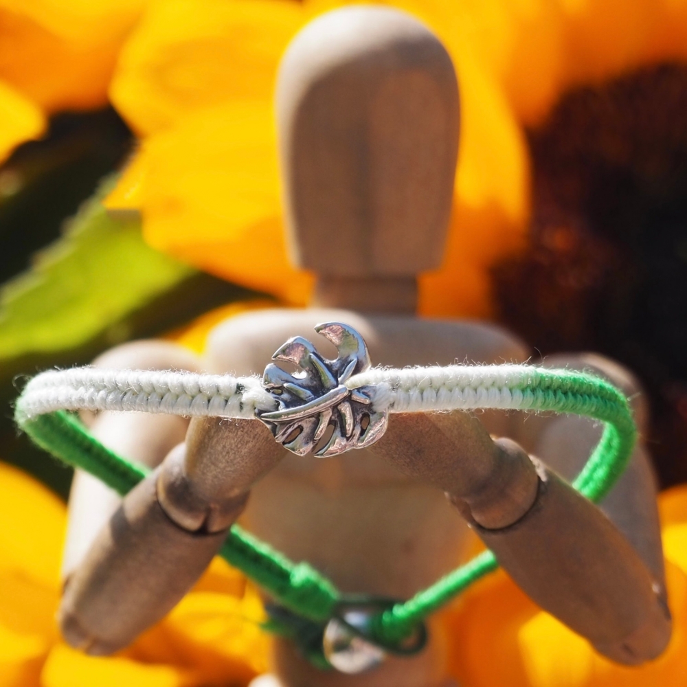 Fine silver monastera leaf charm on a vivid green friendship bracelet