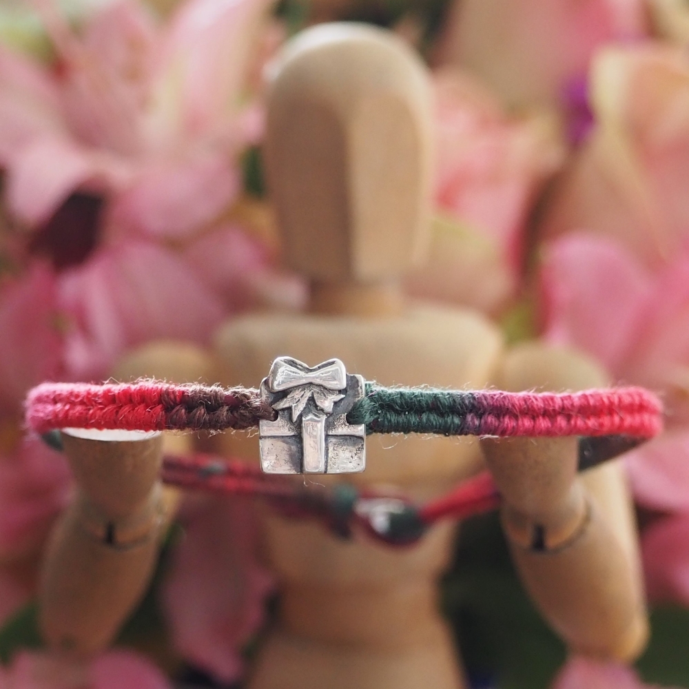Fine silver parcel charm on a red friendship bracelet