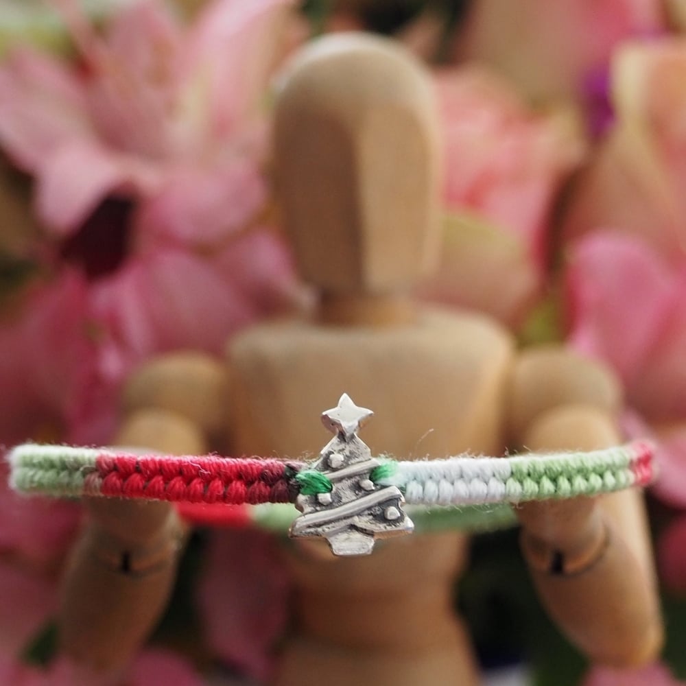 Fine silver Christmas tree charm on a red friendship bracelet
