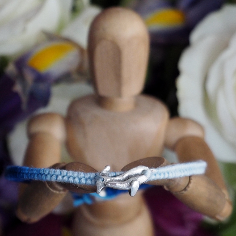 Fine silver narwhal charm on a blue friendship bracelet