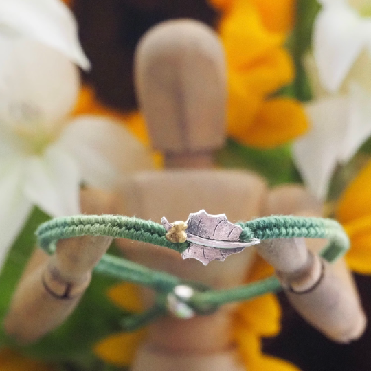 Fine silver holly leaf charm on a green friendship bracelet