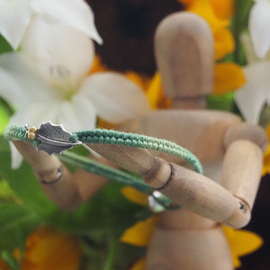 Fine silver holly leaf charm on a green friendship bracelet