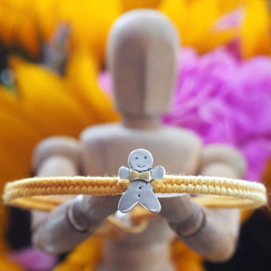 Fine silver gingerbread man on a yellow friendship bracelet