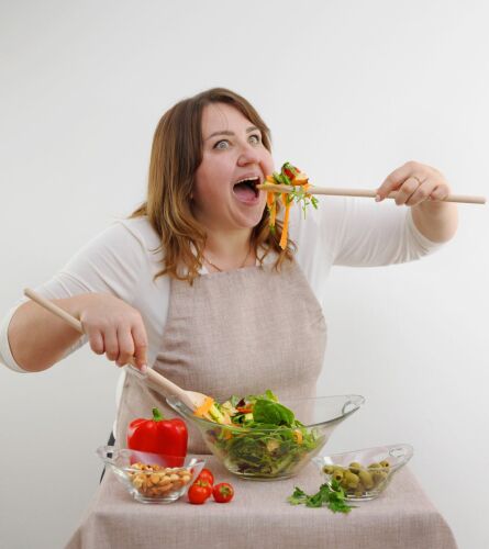 funny-cheerful-woman-eating-salad-wooden-spoon-crop