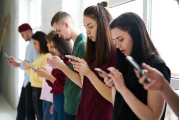Group-of-young-male-and-female-students-using-application-on-modern-gadgets