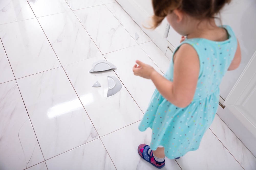 broken plate with child girl in blue dress looking at it