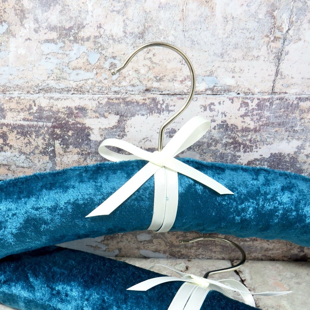 A pair of padded coat hangers in teal velvet.