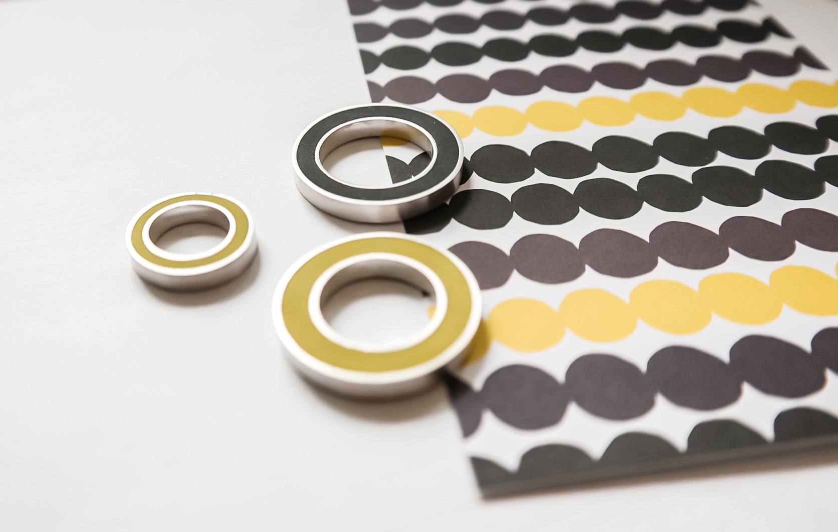Colour block pendants in yellow and black against an abstract yellow and grey print by Marimekko