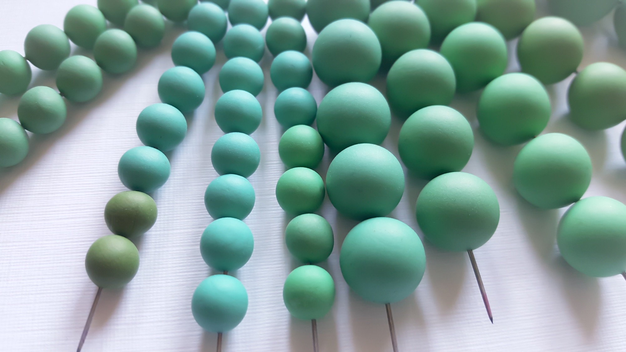 Handmade round polymer clay beads in shades of blue and green