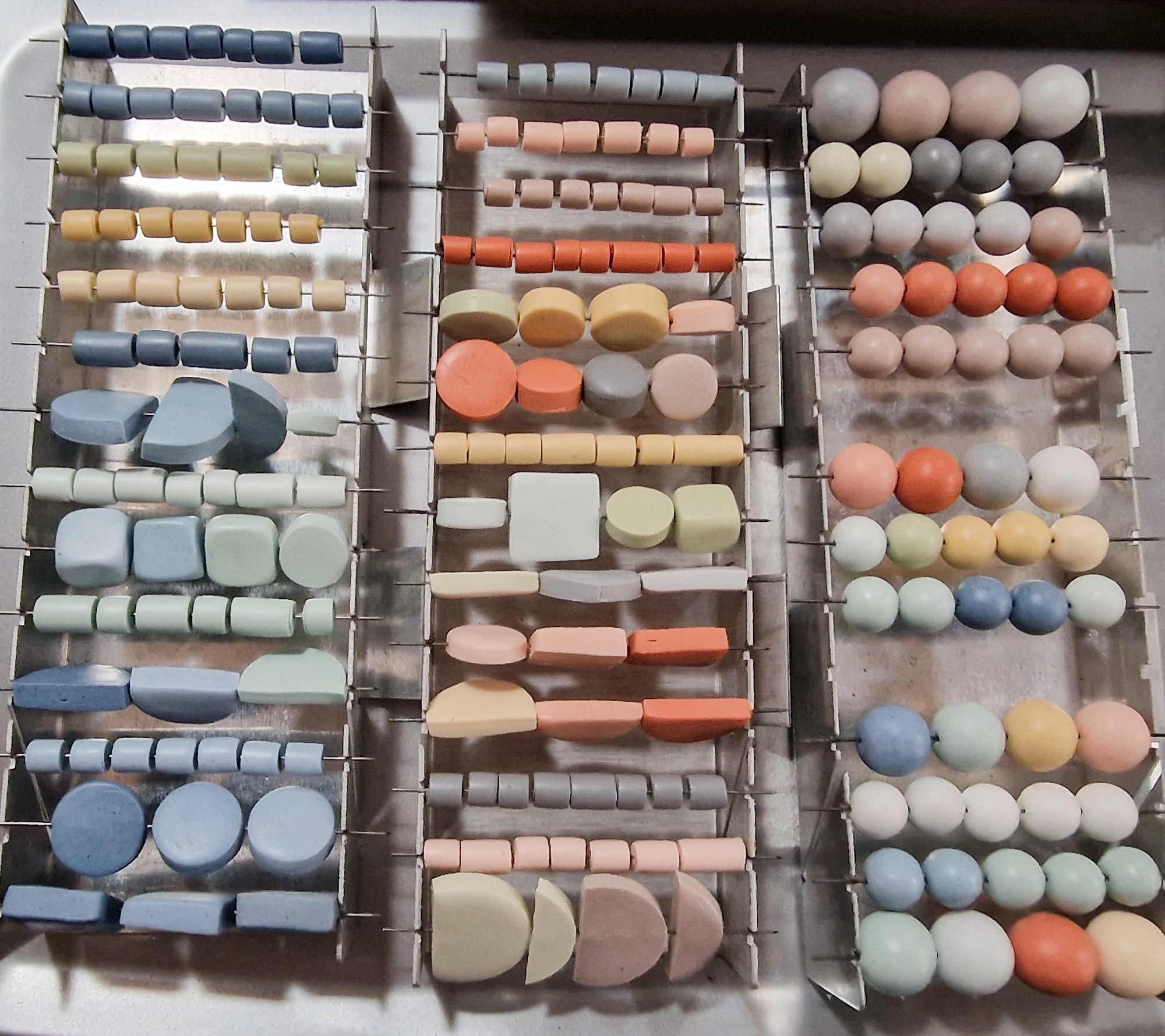 Handmade polymer clay beads on racks waiting to be fired