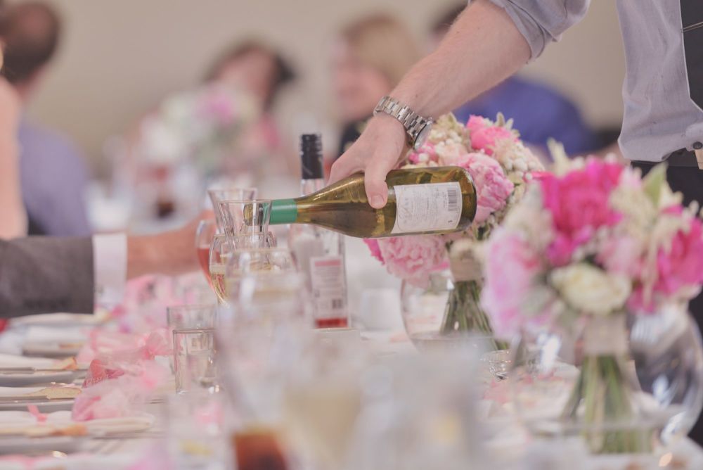 Man Pouring Wine At Wedding Restaurant Table